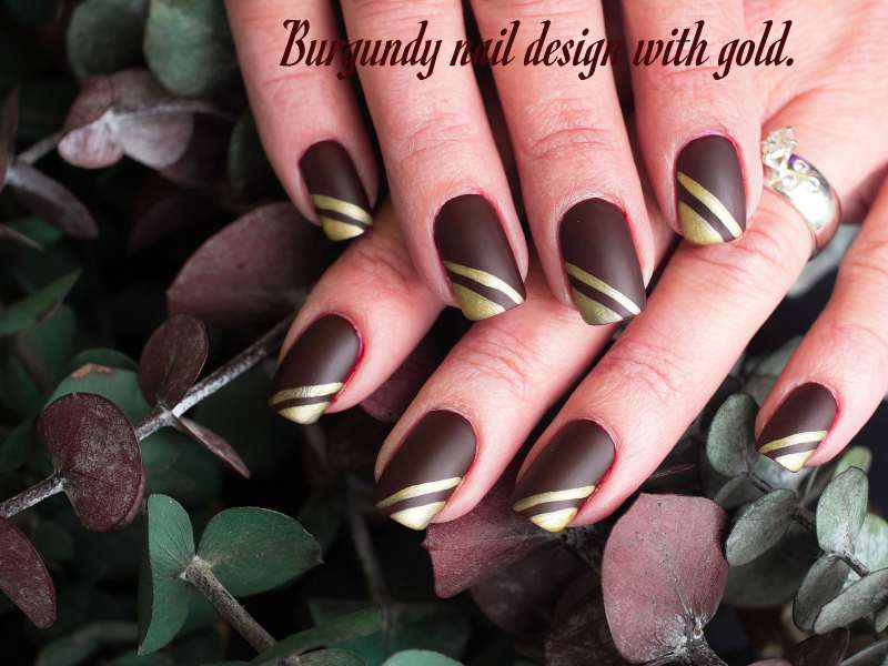 Burgundy nail design with gold.